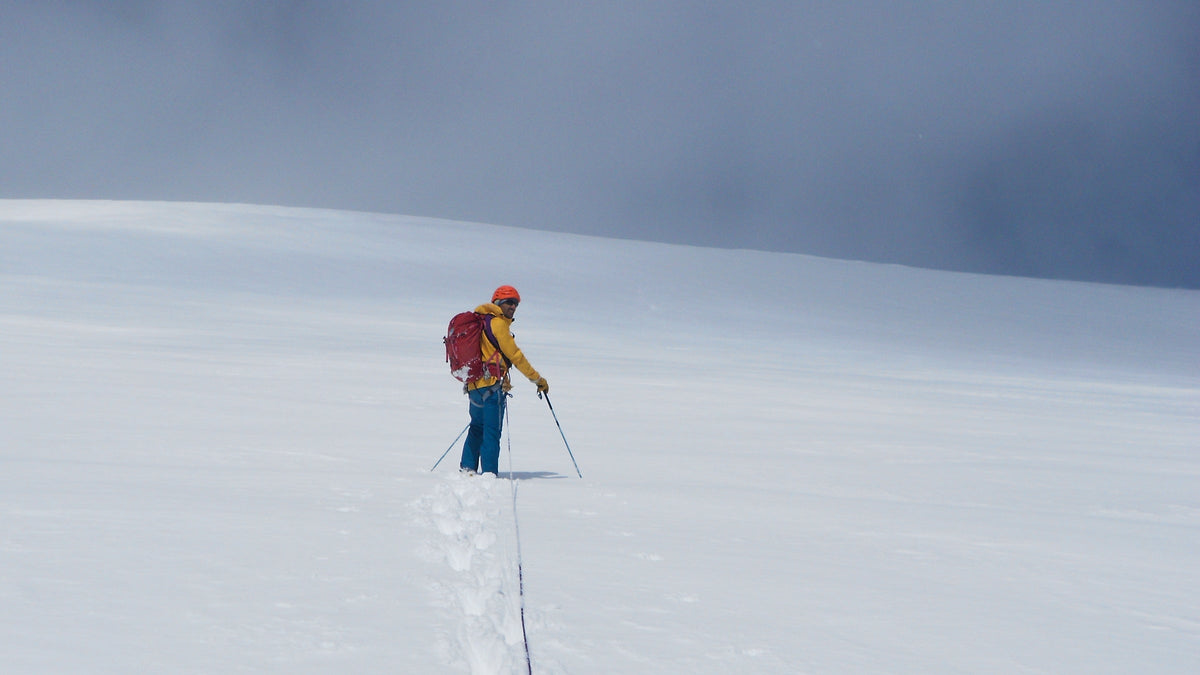 Alpiniste seul sur un champ de neige, trace de corde derrière lui