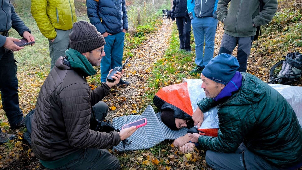 Formateur et stagiaires autour d'une victime simulée lors d'un exercice de secourisme en forêt