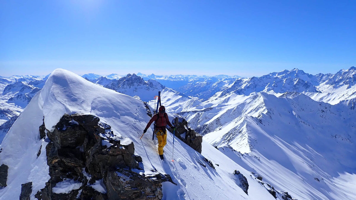 Skieur-alpiniste skis sur le sac sur une arête enneigée, panorama sur les sommets de Maurienne