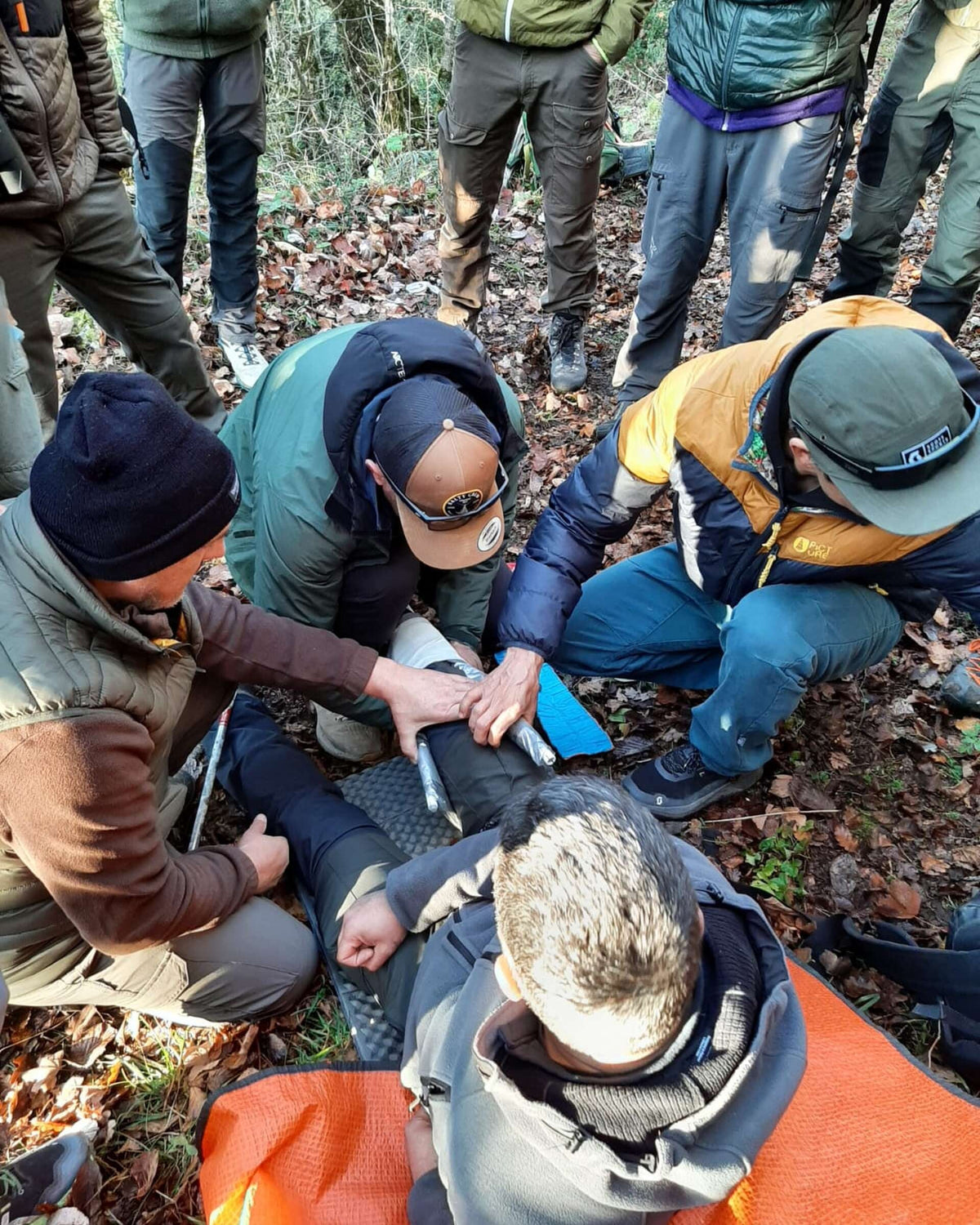 Stagiaires prenant en charge une victime au sol pendant un exercice de secours en pleine nature