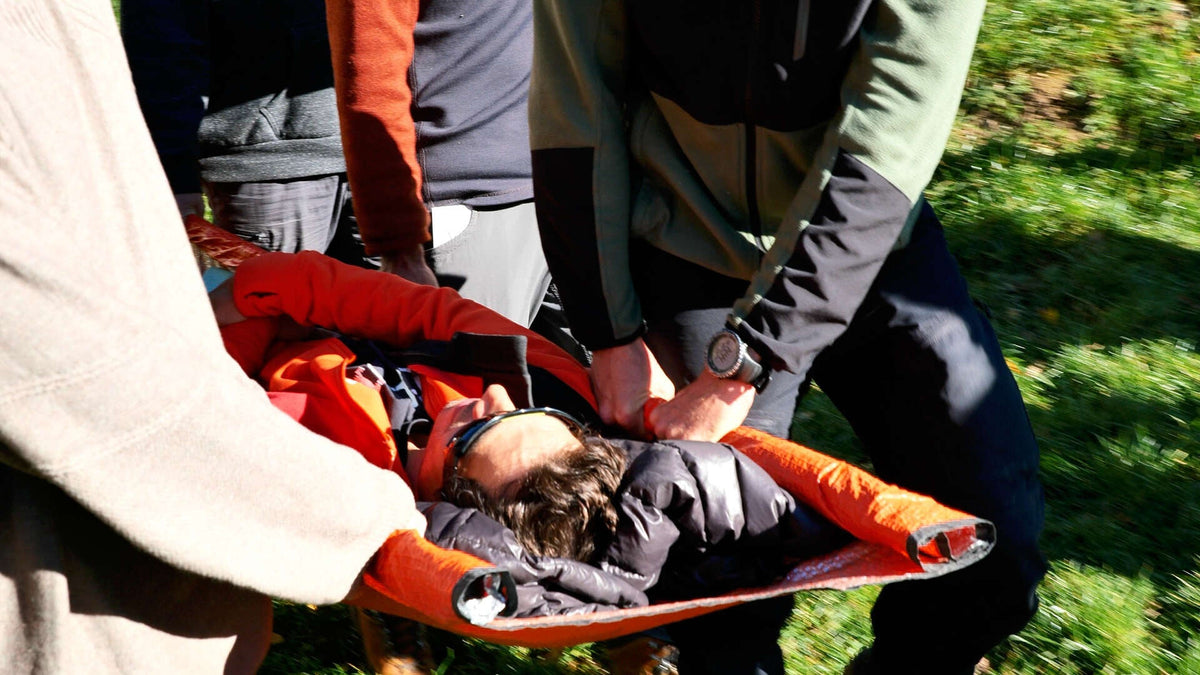 Évacuation d'une victime sur un brancard improvisé dans l'herbe