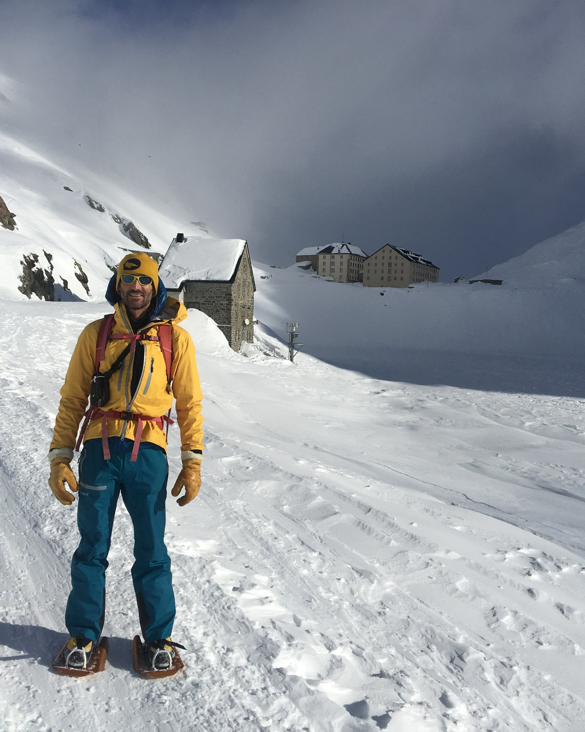 Skieur en veste jaune sur une trace de montée près d'un refuge