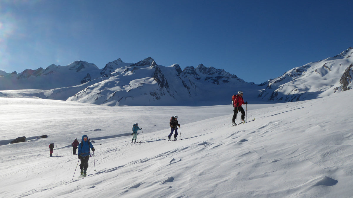 Groupe de skieurs de randonnée progressant sur un vaste glacier