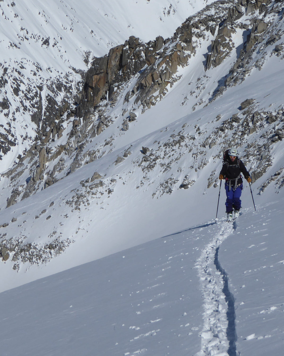 Trace de montée menant un skieur au fond d'un vallon enneigé