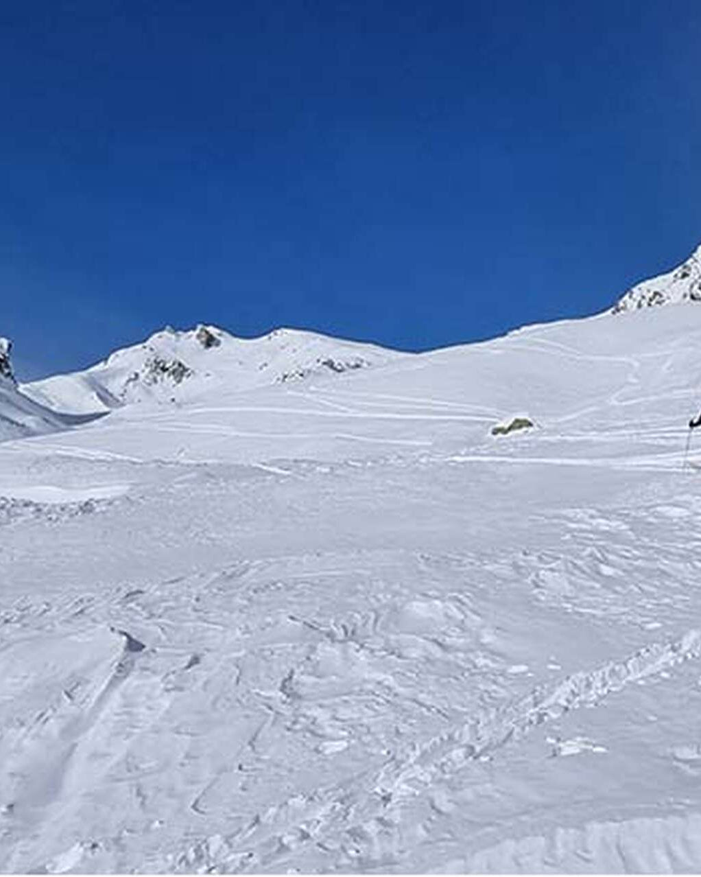 Deux skieurs de randonnée en montée dans un vaste vallon enneigé