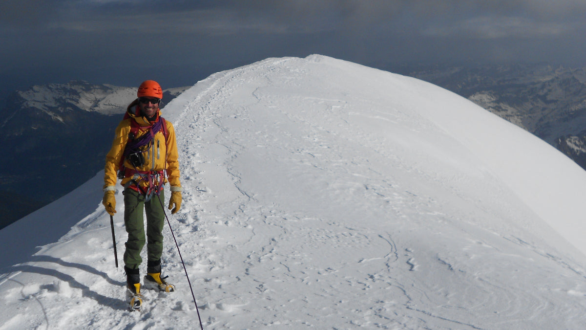 Alpiniste en crampons sur un dôme de neige, piolet à la main