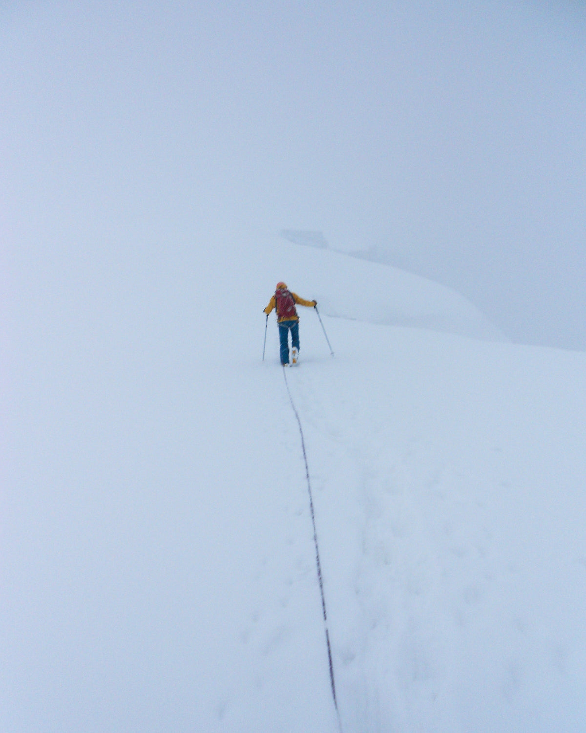 Silhouette d'alpiniste au loin sur une pente de neige immaculée