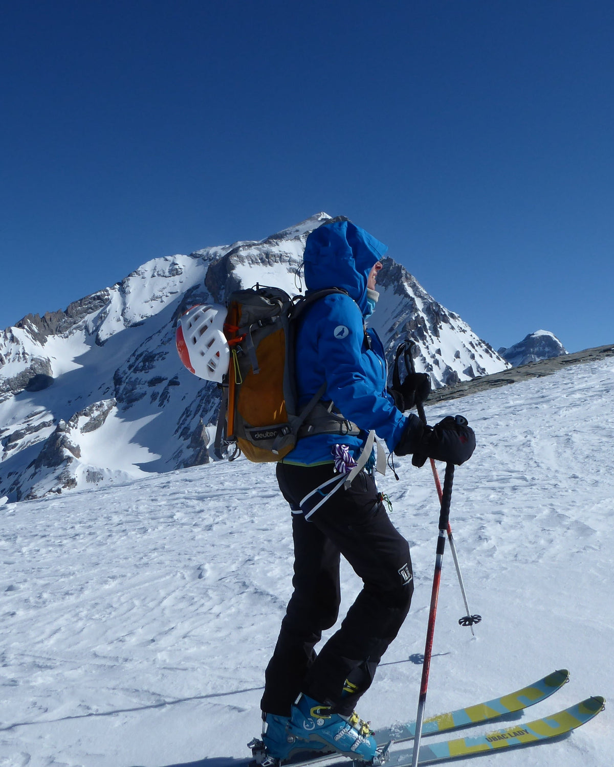 Skieur de randonnée en montée devant des sommets enneigés