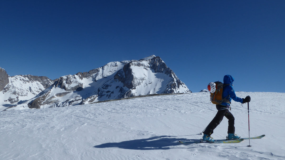 Skieur de randonnée face à un panorama de sommets enneigés