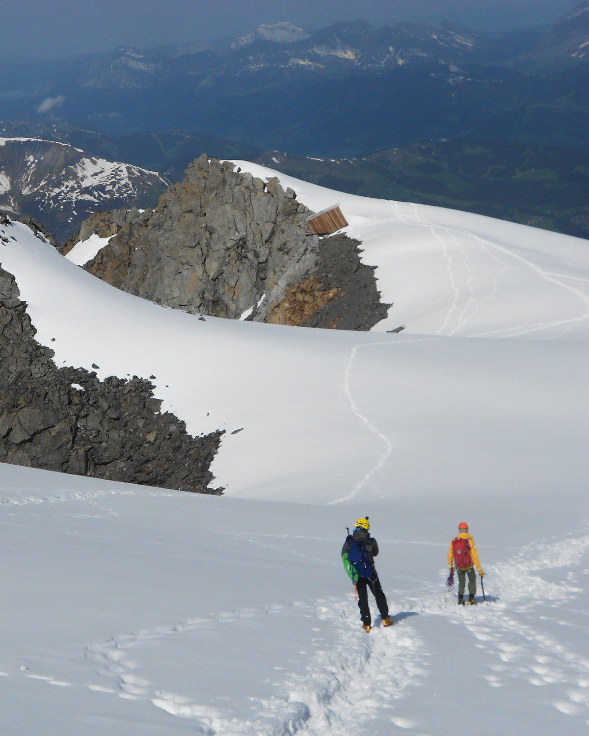 Deux alpinistes encordés sur un glacier enneigé au pied de sommets rocheux