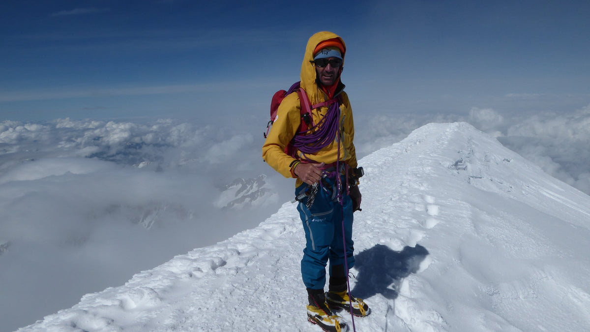 Alpiniste en crampons posant au sommet d'une arête neigeuse ensoleillée