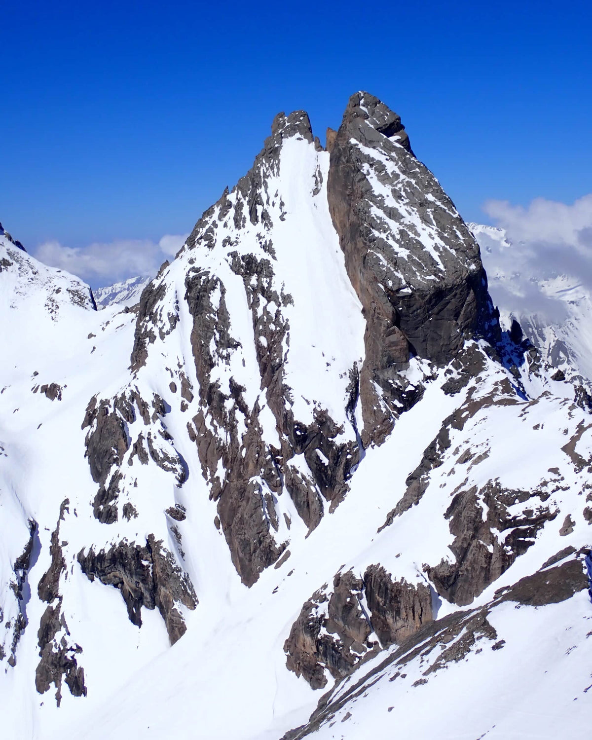 Aiguille rocheuse enneigée dominant les pentes de ski de randonnée