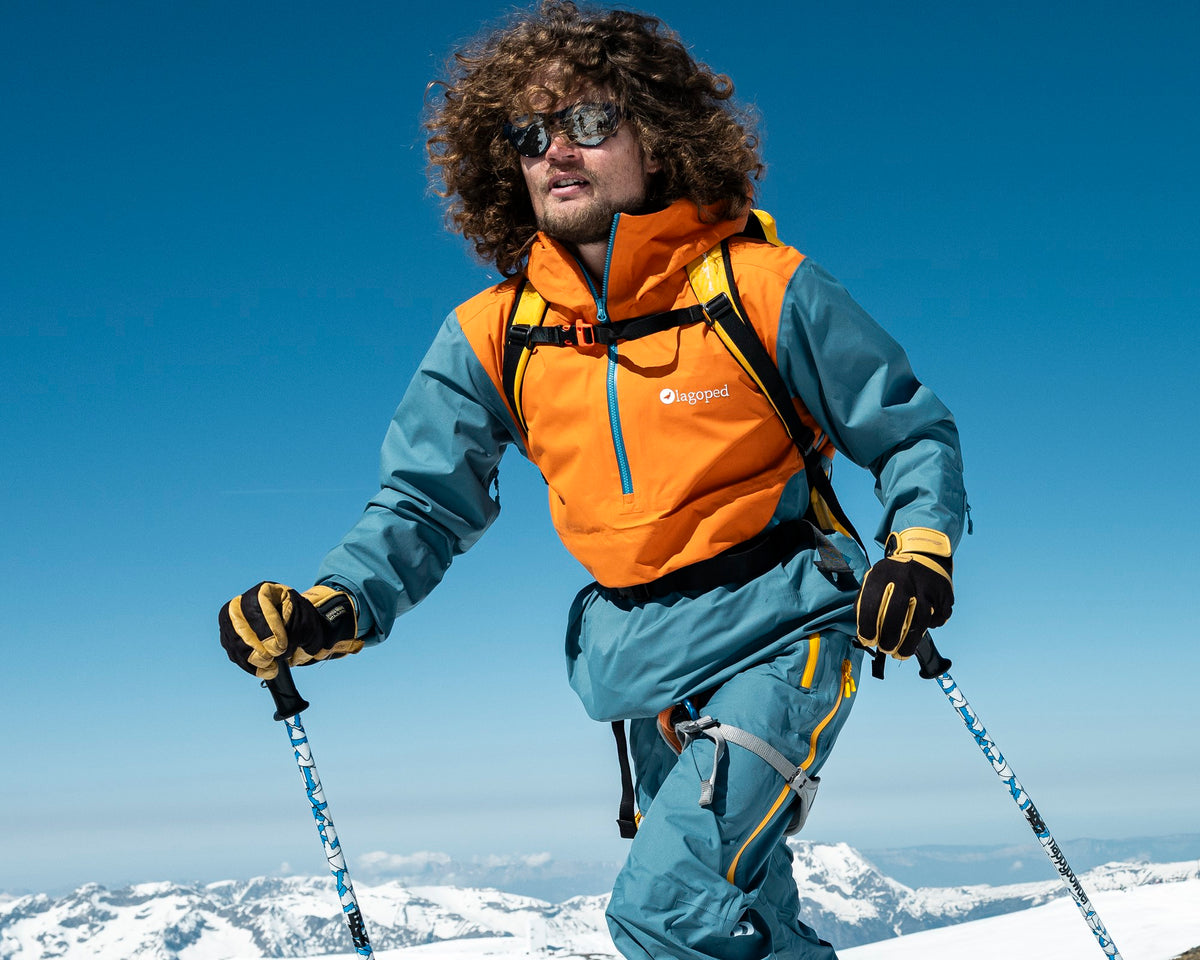 Homme en ski de randonnée portant l'anorak freeride Lagoped FOGOLY bicolore, montée en peaux sous le ciel bleu
