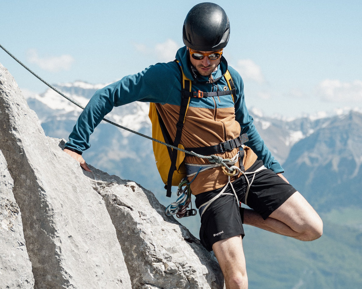 Homme en alpinisme portant la polaire technique à capuche Lagoped PHANTOM HOODIE camel, encordé, il enjambe un rocher calcaire