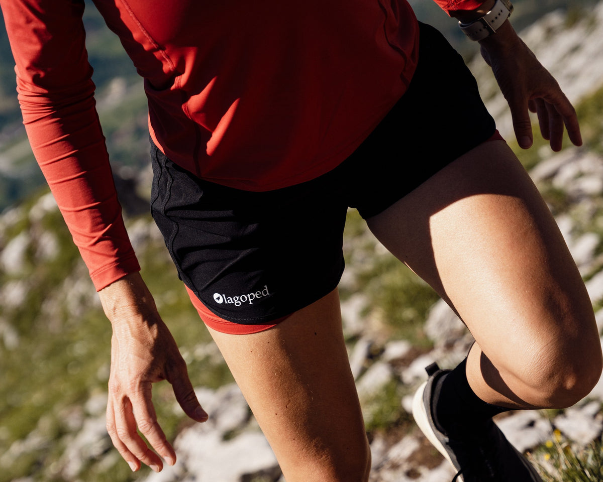 Femme en trail portant le short de trail Lagoped MILVUS, course en montée sur un sentier rocailleux de montagne