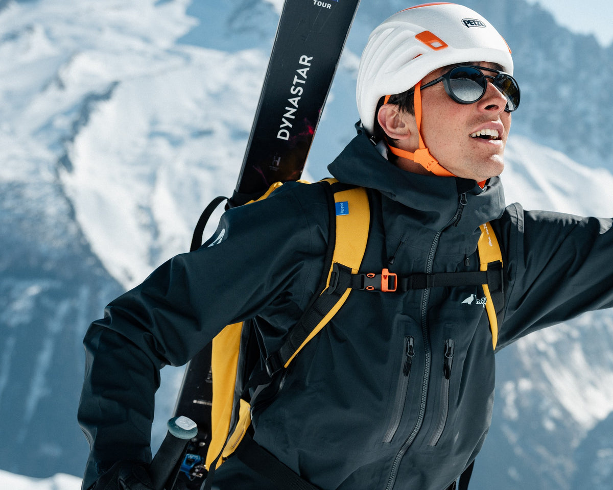 Homme en ski de randonnée portant la veste de montagne Lagoped EVE graphite, skis sur le sac, en hiver en montagne