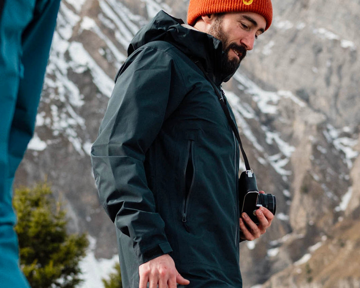 Homme en randonnée hivernale portant la veste 3/4 Lagoped GRAND TETRAS graphite, appareil photo à la main, en montagne