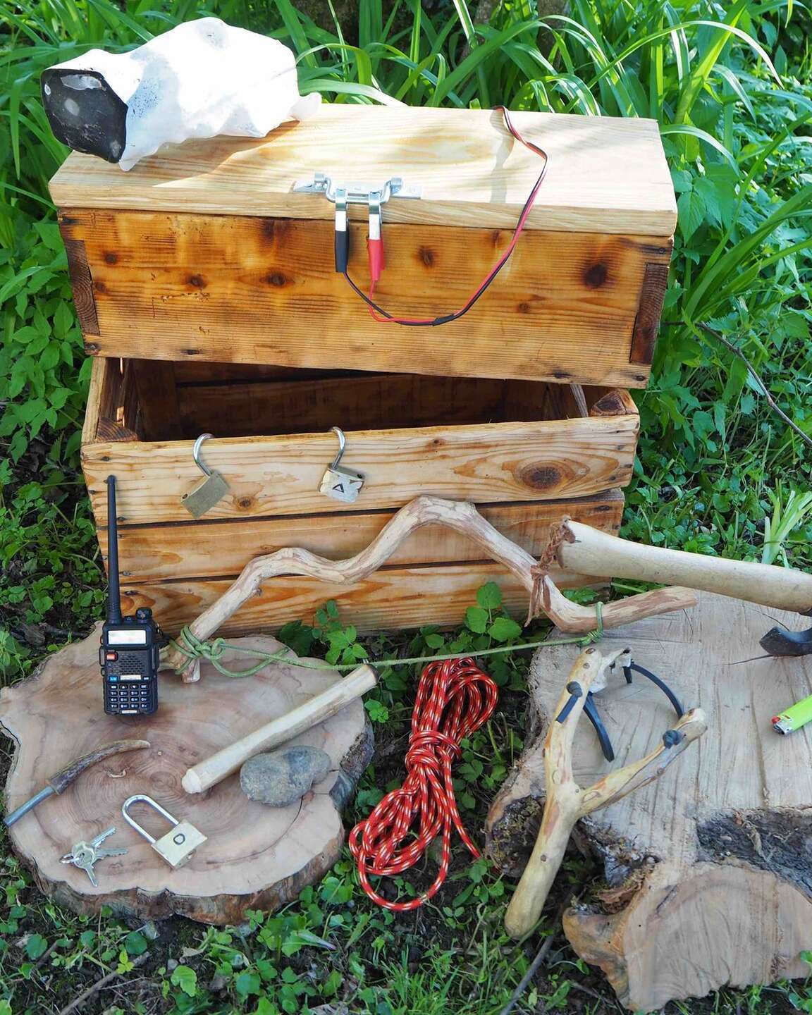 Coffre en bois, cordes et objets d'énigme posés dans l'herbe pour un escape game nature