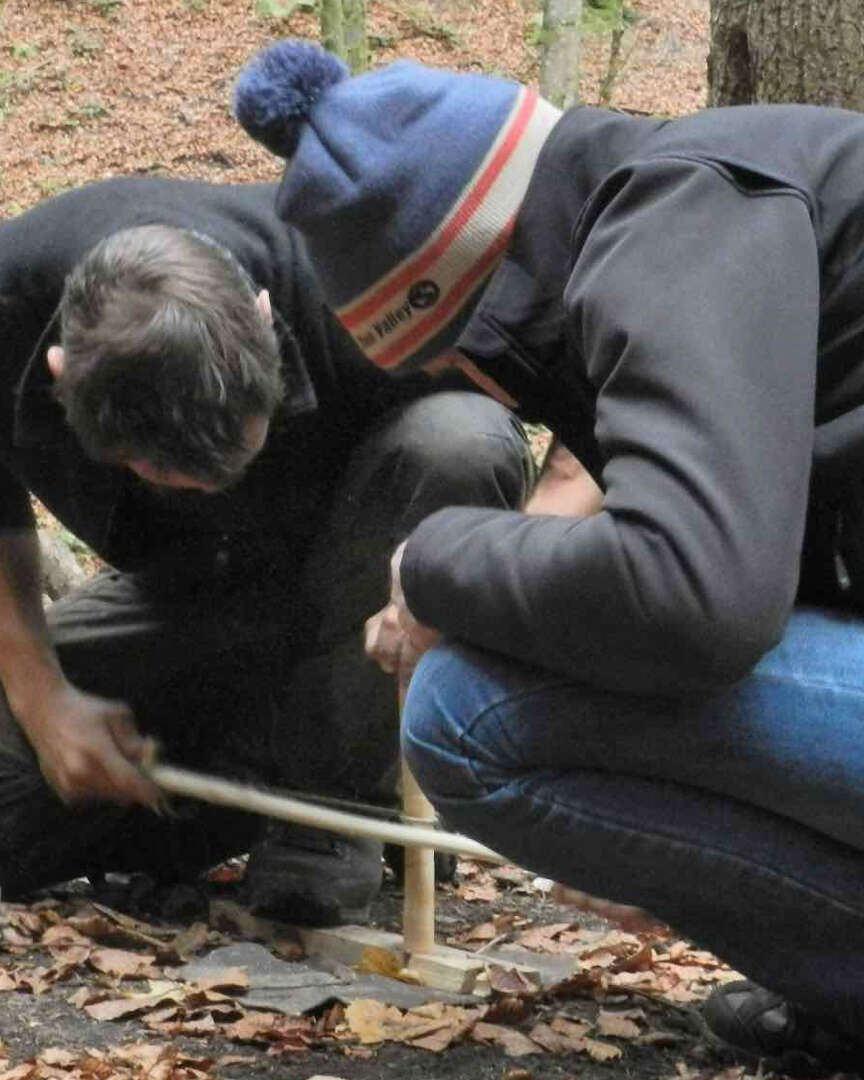 Allumage d'un feu par friction avec un archet en bois au sol de la forêt